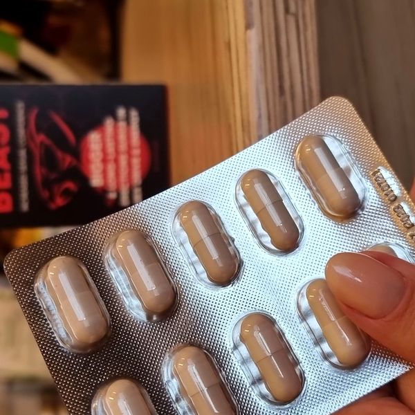 Blíster de cápsulas marrones de Alpha Beast sujeto con los dedos