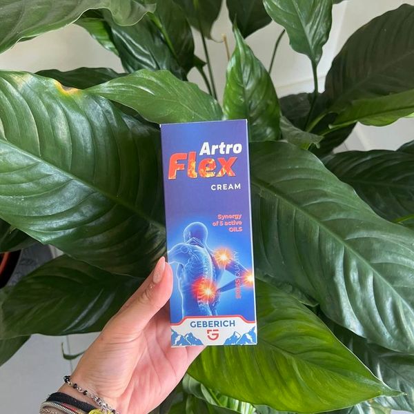 Mano que sostiene la caja de ArtroFlex Cream entre hojas verdes