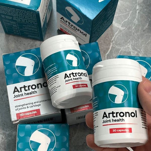 Mano que sostiene un bote de Artronol entre varias cajas