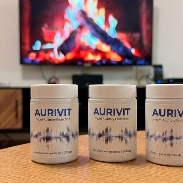 Tres botes de Aurivit sobre una mesa, con una chimenea al fondo