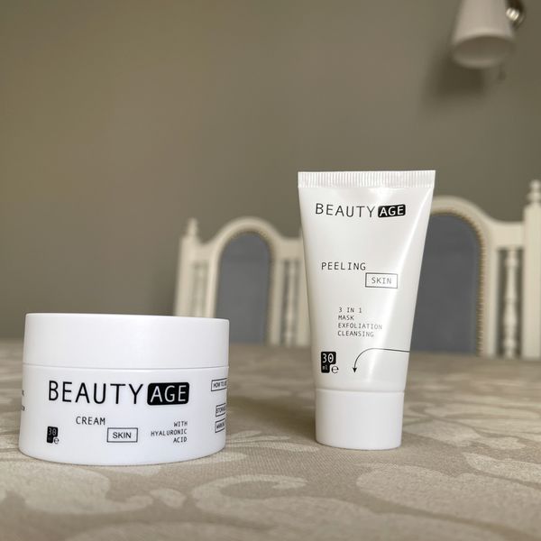 Tarro de crema y tubo de peeling 3 en 1 de Beauty Age Complex, blancos, sobre una mesa con mantel beige