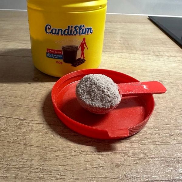Bote amarillo de CandiSlim con su cacito lleno de polvo sobre la tapa roja