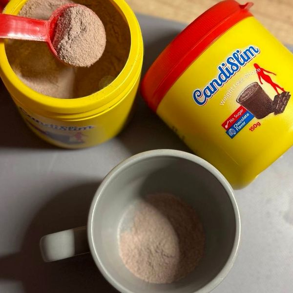 Bote de CandiSlim abierto con el cacito y una taza con el polvo