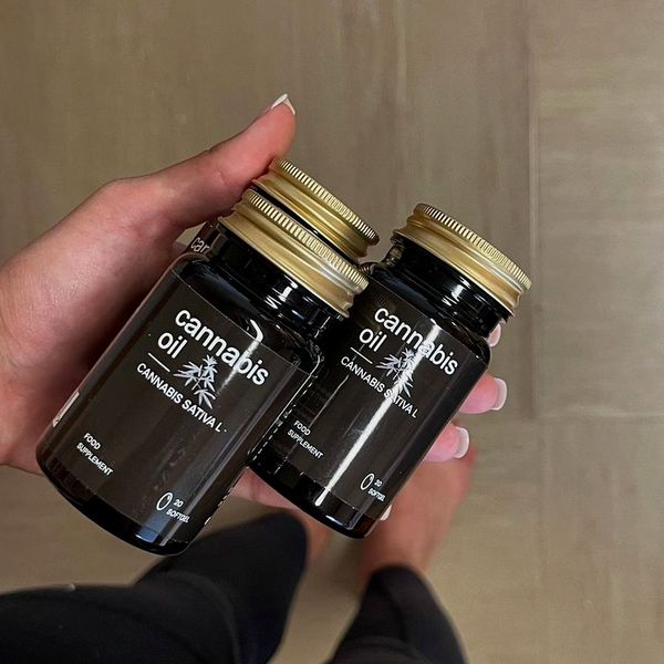 Mano que sostiene dos tarros de Cannabis Oil