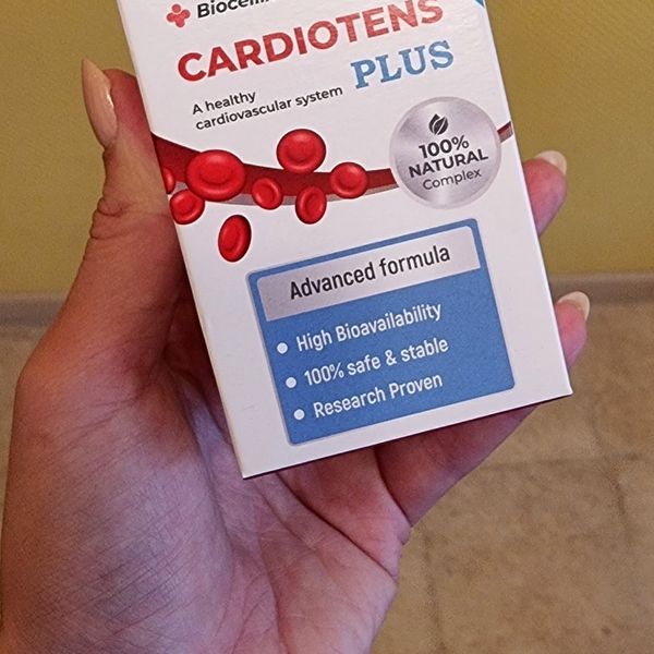 Mano que sostiene la caja blanca de Cardiotens Plus con glóbulos rojos dibujados