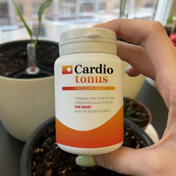 Mano que sostiene el bote blanco y naranja de Cardiotonus