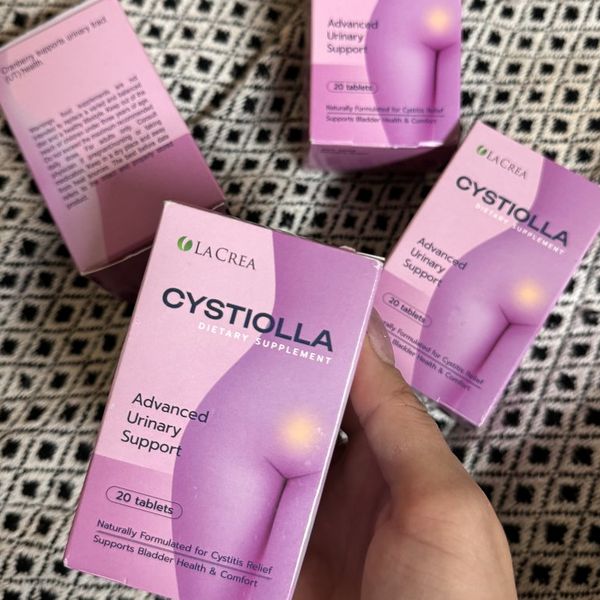 Mano que sostiene la caja rosa de Cystiolla junto a otras