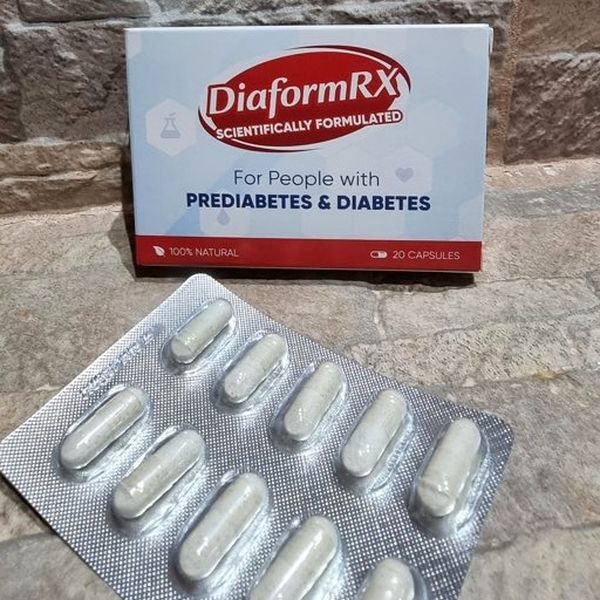 Caja blanca y roja de DiaformRX, 20 cápsulas, en una repisa de piedra con un blíster de cápsulas delante
