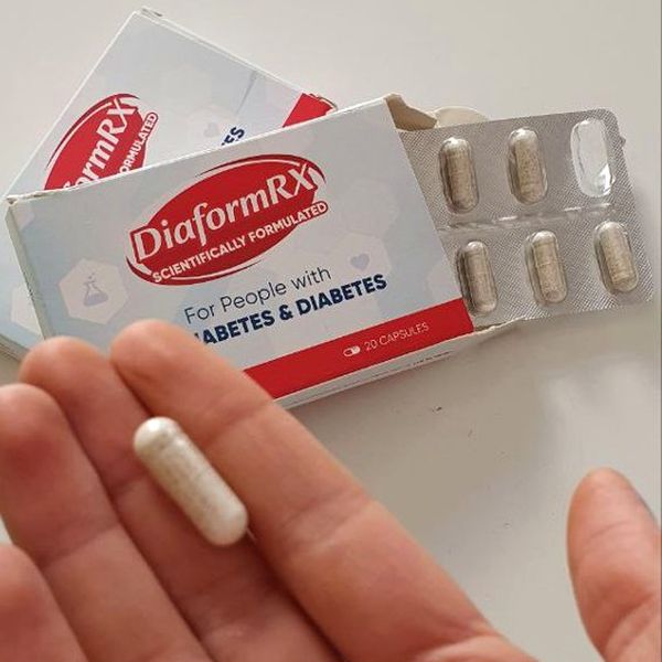 Caja de DiaformRX abierta con el blíster y una cápsula en la palma de la mano