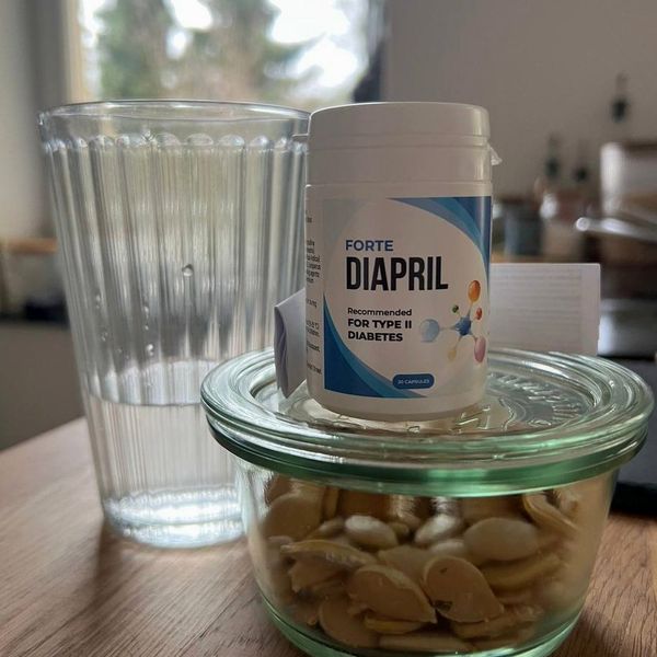 Bote blanco y azul de Diapril, 20 cápsulas, sobre un tarro de pipas de calabaza y junto a un vaso de agua