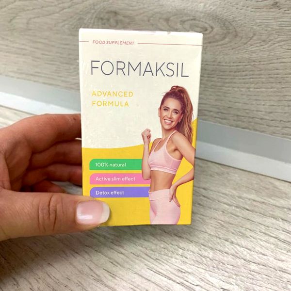 Mano que sostiene la caja de Formaksil sobre una mesa de madera