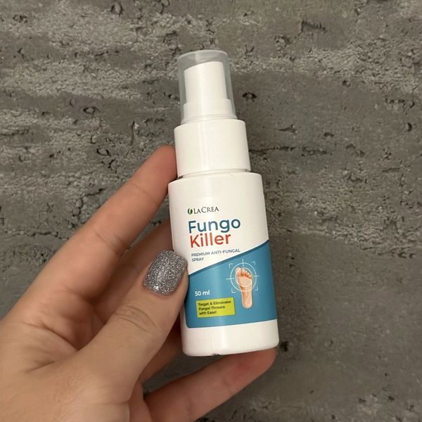 Mano que sostiene el espray de Fungo Killer ante una pared gris