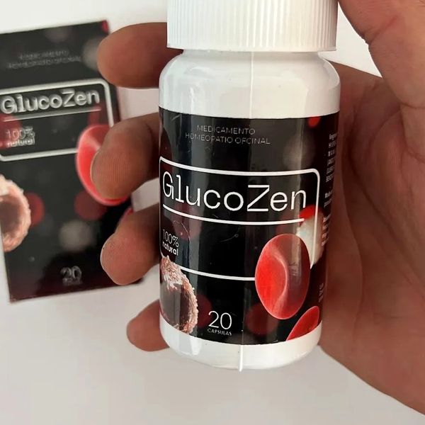 Mano que sostiene el bote blanco de GlucoZen, de etiqueta negra con glóbulos rojos, ante su caja negra