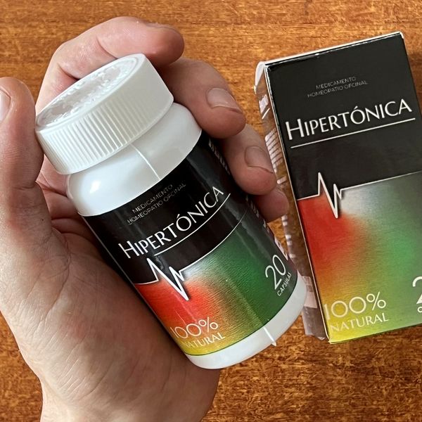 Mano que sostiene el bote de Hipertónica junto a su caja negra
