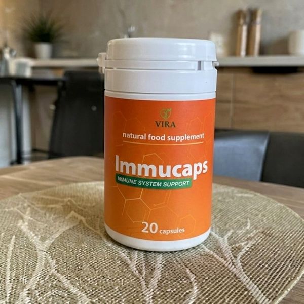 Bote naranja de Immucaps sobre una mesa con mantel de encaje