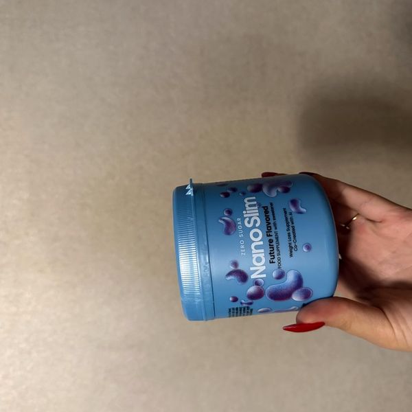 Mano que sostiene el bote azul de Nano Slim tumbado