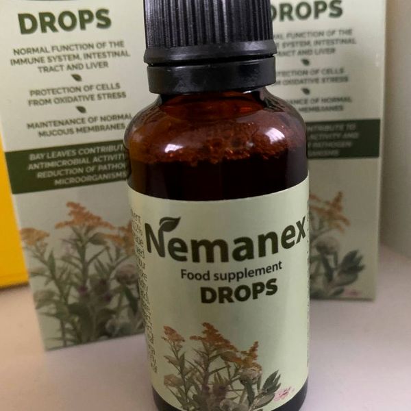 Frasco ámbar de Nemanex con tapón cuentagotas negro, en primer plano, delante de dos cajas verdes
