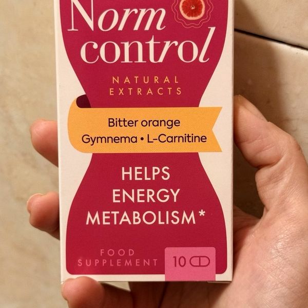 Mano que sostiene la caja fucsia de NormControl de 10 cápsulas