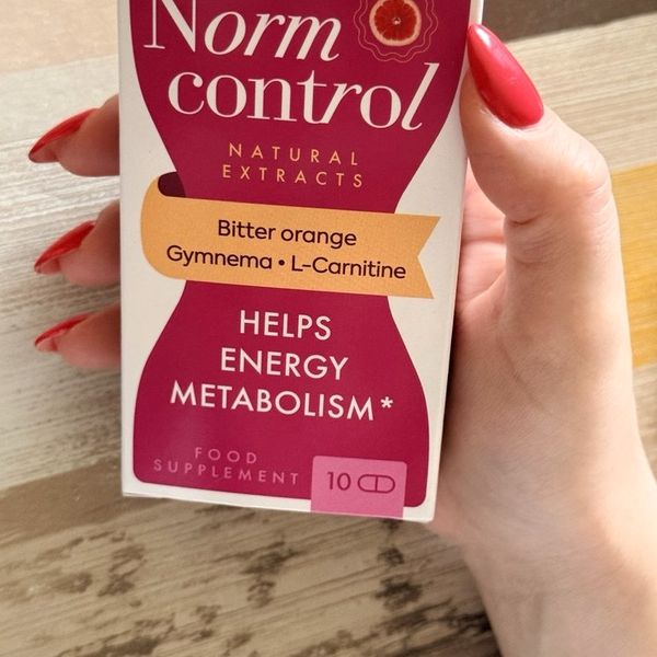Caja de NormControl sujeta con la mano junto a una ventana