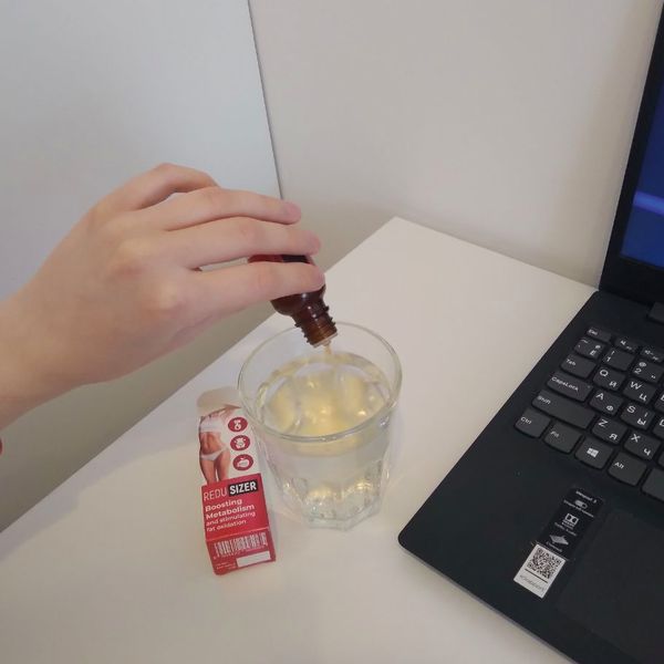 Gotas de Redusizer en un vaso junto a un portátil