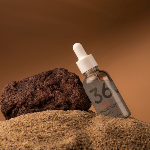 Frasco de Simpla 360 apoyado en una piedra volcánica