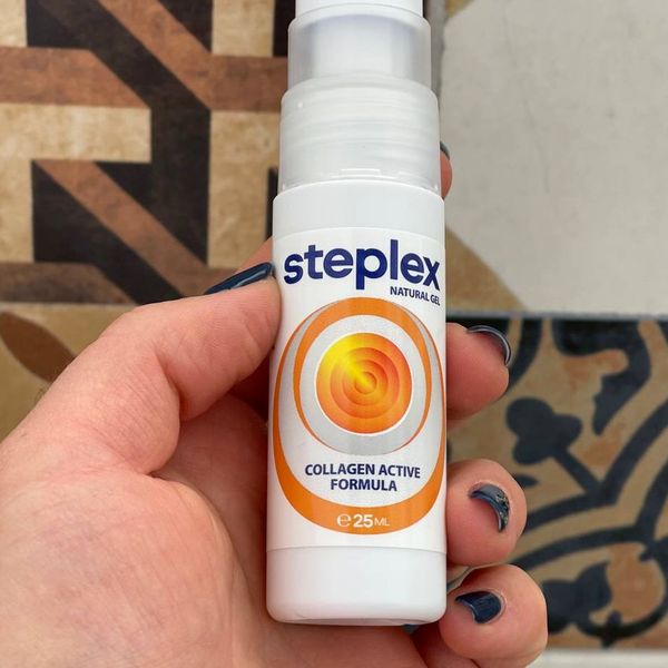 Mano con el frasco blanco de Steplex, de 25 ml, y su logotipo de círculos naranjas, ante unas baldosas