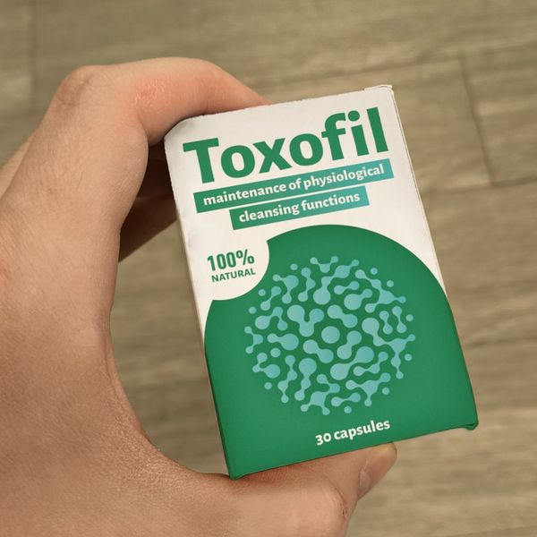Mano que sostiene la caja verde y blanca de Toxofil de 30 cápsulas