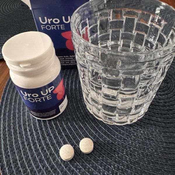Bote de Uro UP Forte abierto con dos comprimidos y un vaso de agua