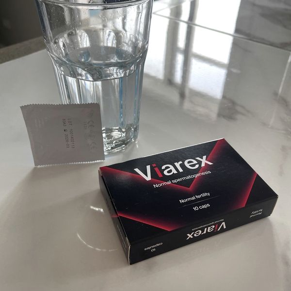 Caja de Viarex junto a un vaso de agua y el prospecto